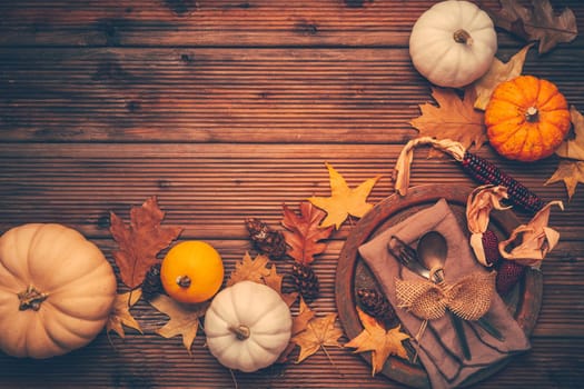 Autumn flat lay with plate setting, pumpkins and autumn leaves with copy space