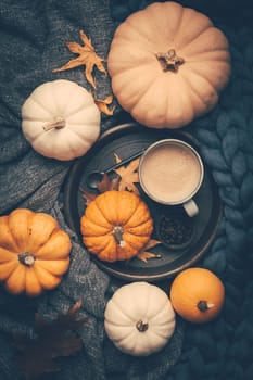 Autumn flat lay with cup of coffee, pumpkins and cuddle blanket on wooden background