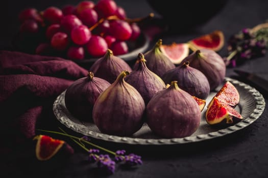 Organic fresh figs with red grapes and lavender on dark background