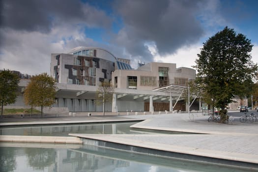 The reflecting pools in front of the Scottish Parliament building in Edinburgh with blue sky and storm clouds looming