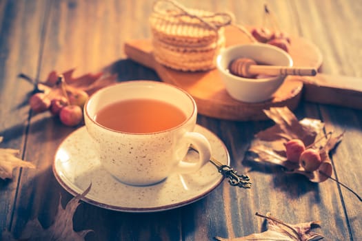 Hot tea with honey, homemade wafer biscuit and autumn leaves on wooden background