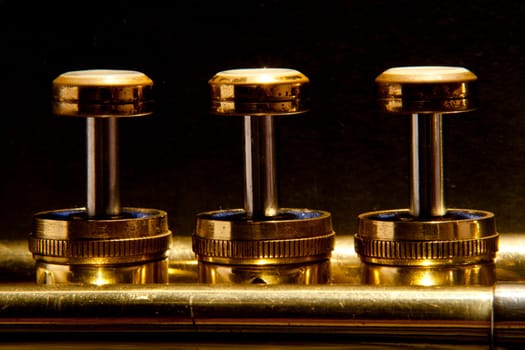 The valves on a trumpet in a line