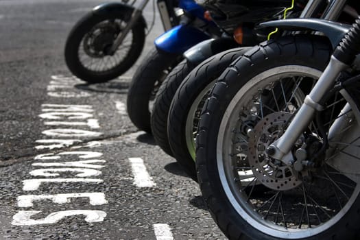 The front wheels of motorcycles parked in a bay