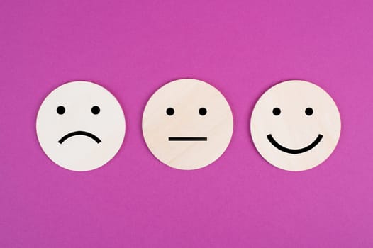 Three faces, smiling, sad in different colors on a pink background, copy space, rating, communication, customer feedback