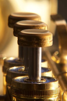 Three trumpet valves brass in a line with differential focus