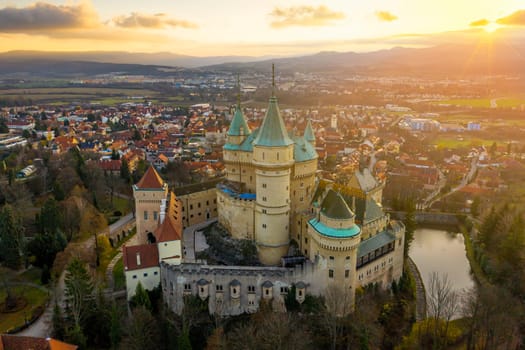 European medieval castle at Bojnice, Slovakia, with sun low above the horizon. Chateau overlooking town in soft morning light.