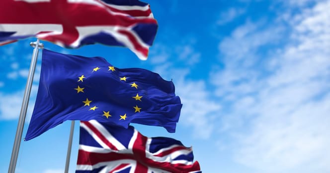 The Flag of the European Union Waving Between Two Flags of United Kingdom with clear sky on the background. International relations and diplomacy. Brexit