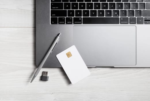 Online business concept. Blank bank card, pen, flash drive and laptop keyboard.