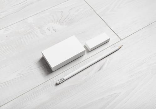 Photo of blank business cards, pencil and eraser on wooden background.