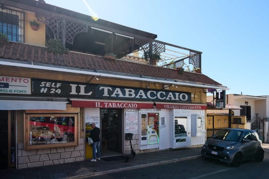 Civitavecchia. Italy - January 26, 2025: Tobacco shop in Civitavecchia, Italy, featuring a self-service kiosk and 24-hour service. The storefront includes signage and a small car parked in front.
