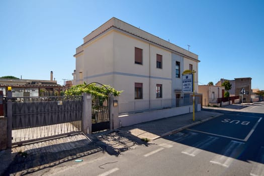 Civitavecchia, Italy - January 26, 2025: Residential building and bus stop, on a sunny day in the urban environment of Civitavecchia, Italy. Architectural details and the surrounding area are visible.