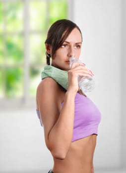 Beautiful sporty woman drinking water and doing sport