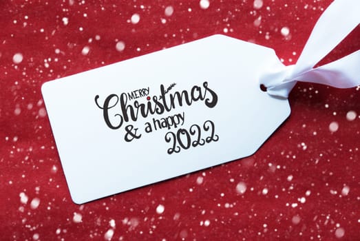 Label With English Calligraphy Merry Christmas And A Happy 2022. Red Textured Background With Snowflakes