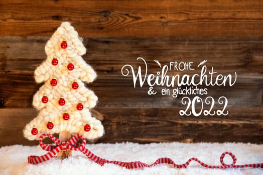 German Calligraphy Frohe Weihnachten Und Ein Glueckliches 2022 Means Merry Christmas And A Happy 2022. White Fabric Christmas Tree With Red Ball Ornament. Brown Rustic Wooden Background With Snow