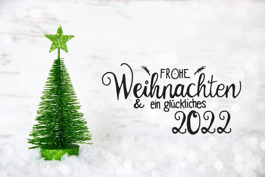 German Calligraphy Frohe Weihnachten Und Ein Glueckliches 2022 Means Merry Christmas And A Happy 2022. One Green Christmas Tree With Star Ornament. Lights Background With Snow