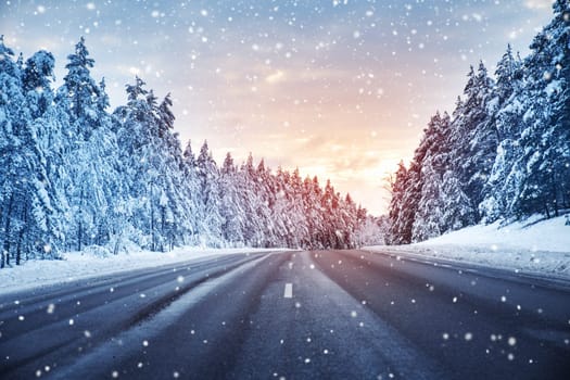 Beautiful view of the snowy curve country road in snowfall. Winter way in natural park.