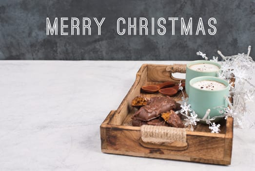 Coffee cups and chocolate coated gingerbread in a wooden basket, christmas season empty copy space, book with a pen