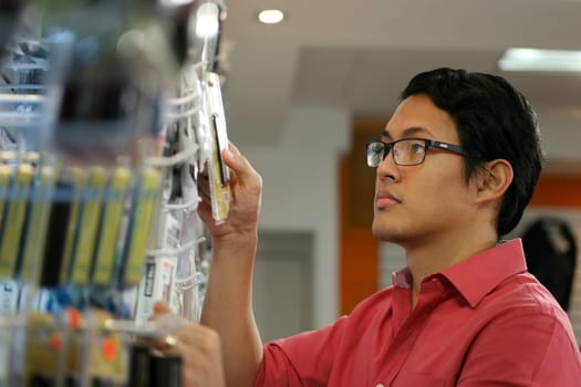 Chinese sales clerk working in computer store, arranging and ordering cables and usb flash memory drives on shelf