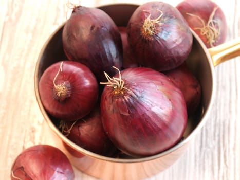 Fresh red onions in a copper pan