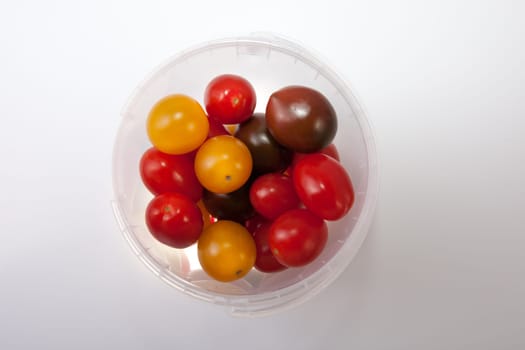 Bucket of colorful cherry tomatoes. Isolated over white background