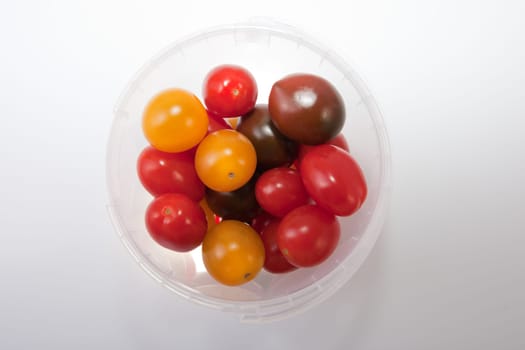 Bucket of colorful cherry tomatoes. Isolated over white background
