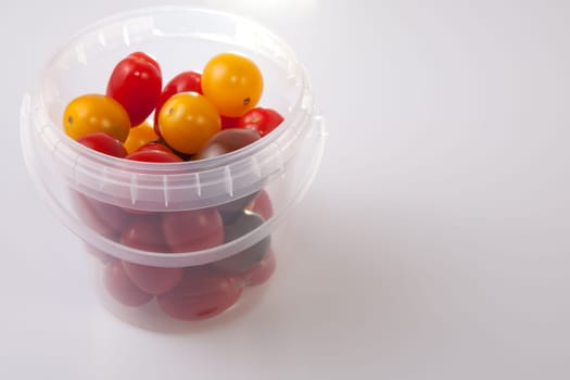 Bucket of colorful cherry tomatoes. Isolated over white background