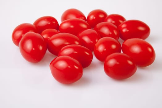Handful of red shiny cherry tomatoes. Isolated over white background