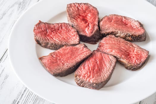 Tender fillet mignon steak, perfectly cooked, sliced, and elegantly presented on a plate