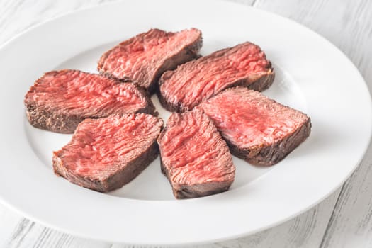 Tender fillet mignon steak, perfectly cooked, sliced, and elegantly presented on a plate