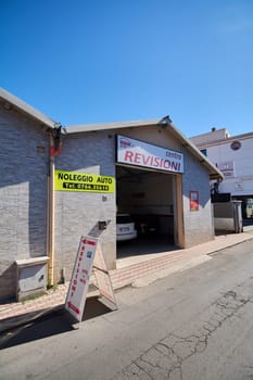 Civitavecchia, Italy - January 26, 2025: Exterior of an Italian vehicle inspection center with clear signage  contact details for rentals and a parking sign in front Urban environment in Civitavecchia