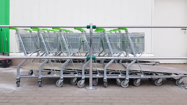 Many metal trolleys are parked in a row near an outdoor construction supermarket. Trading concept