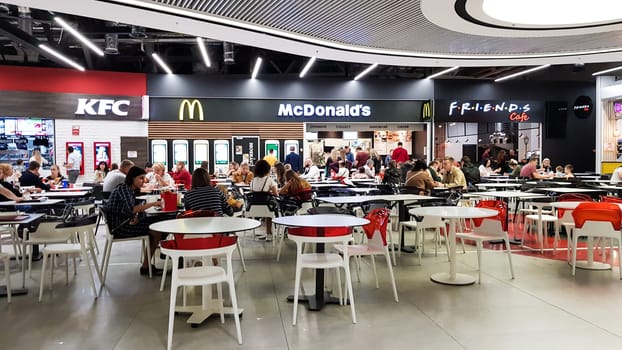 Ukraine, Kiev - March 06, 2020. Fast food area with people in a shopping and entertainment center. McDonald's and KFC. Visitors and guests of the cafe eat fast food at tables in the restaurant