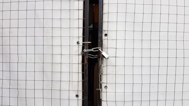 Closed padlock on a hangar from a grid and a white banner.