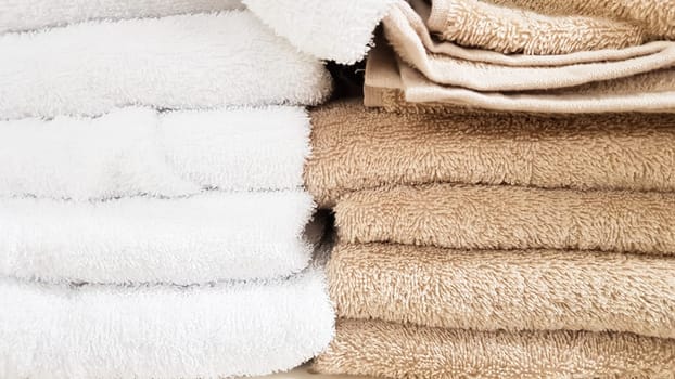 Stacks of fluffy bath towels of various colors in a store window. Terry cotton towels in a stack on the shelves of a supermarket