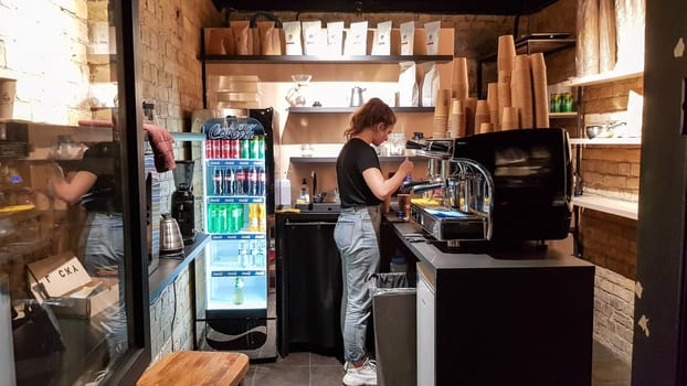 Ukraine, Kiev - March 06, 2020. Prepare a work order concept. Barista girl makes coffee. Cafe and counter with coffee equipment, espresso coffee machine, coffee grinder, cups for making drinks