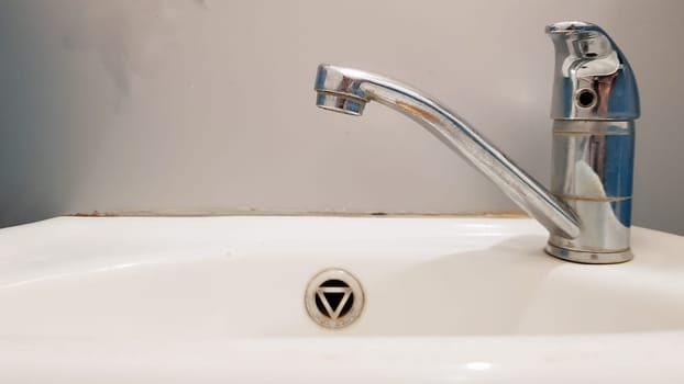 Old and dirty faucet and white ceramic washbasin sink, concept of cleaning, repairing or replacing a bathroom, toilet