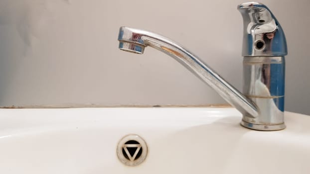 Old and dirty faucet and white ceramic washbasin sink, concept of cleaning, repairing or replacing a bathroom, toilet