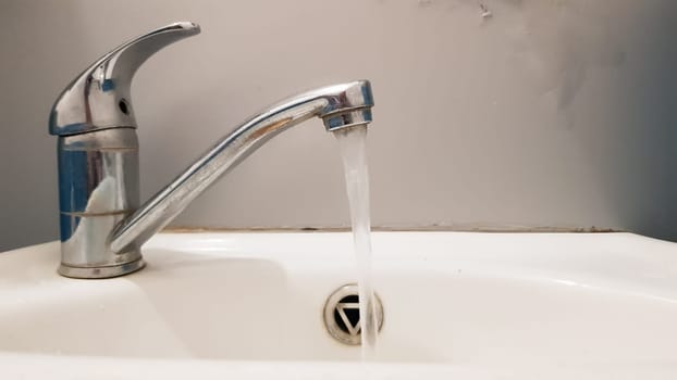 Old and dirty faucet and white ceramic washbasin sink, concept of cleaning, repairing or replacing a bathroom, toilet