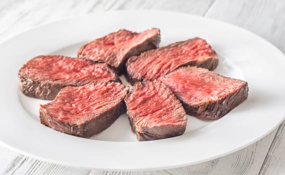 Tender fillet mignon steak, perfectly cooked, sliced, and elegantly presented on a plate