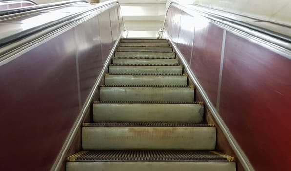 An empty escalator without people at the metro station on the red line of the Kiev metro. Close up of metal steps of an escalator moving from bottom to top.