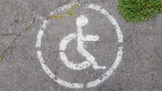 Disabled parking symbol. Disabled bay marked with a person in a wheelchair sign on gray asphalt in a large parking lot close up. view from above.