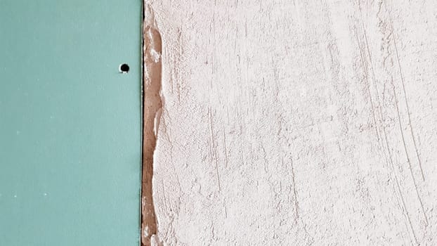 Unfinished wall in a building under construction made of plasterboard. Part of the wall is sheathed with drywall. Drywall is bolted to the wall in anticipation of plaster