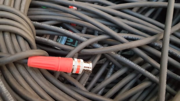 A roll of black cable closeup with a red plug