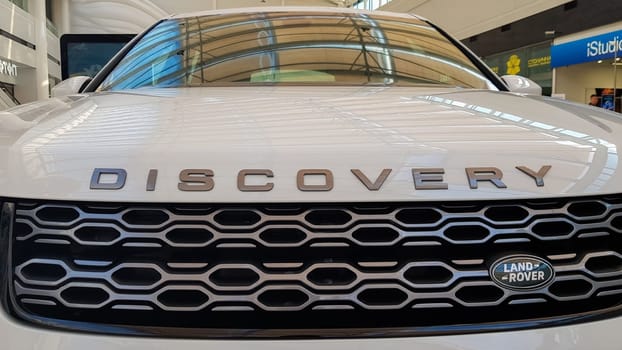 Ukraine, Kiev - March 27, 2020: Land Rover Discovery Sport shiny modern white car at the exhibition. Body, headlights close-up, rear and front view, chrome grille, car logo