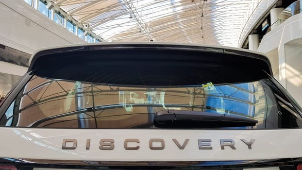 Ukraine, Kiev - March 27, 2020: Land Rover Discovery Sport shiny modern white car at the exhibition. Body, headlights close-up, rear and front view, chrome grille, car logo
