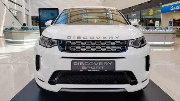 Ukraine, Kiev - March 27, 2020: Land Rover Discovery Sport shiny modern white car at the exhibition. Body, headlights close-up, rear and front view, chrome grille, car logo