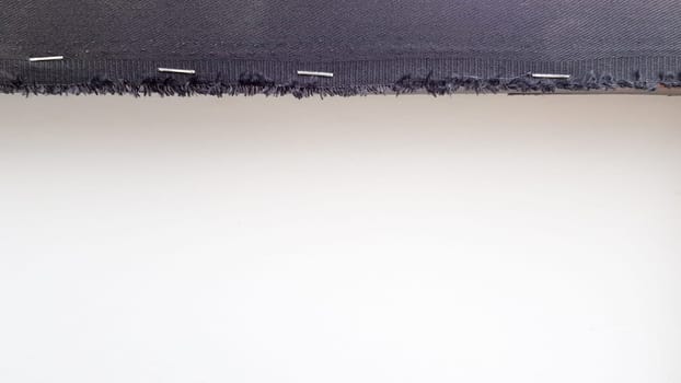White background with a black fabric stripe punched with staples to a wooden plank. Abstract background with copy space