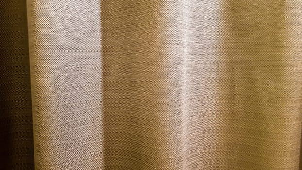 Brown pleated fabric. Thick, pleasant to the touch curtains close-up. Variant of interior decoration. Sewing product.