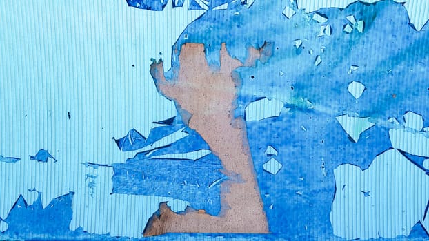 Uneven wavy plastic surface with the remains of flaky film and paper. Abstract obsolete blue background. Copy space, design. Grain blue paint wall background or texture.
