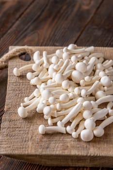 A delicate cluster of bunapi-shimeji mushrooms resting on a wooden surface
